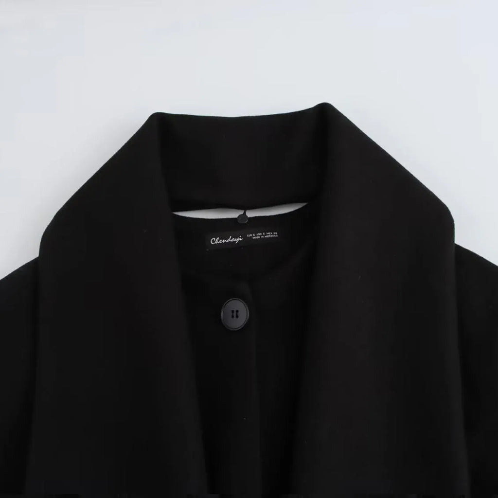Women's long black polyester overcoat with a fluffy artificial fur collar, shown on a hanger.