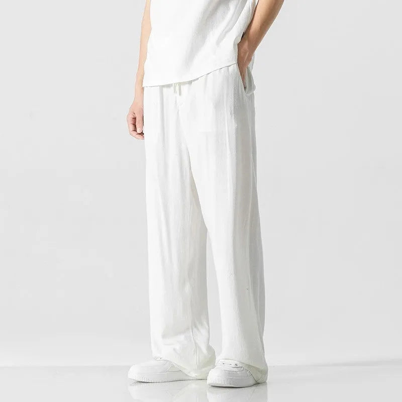 Man wearing beige straight-leg linen bamboo fibre trousers with a drawstring waist and cropped ankle length.