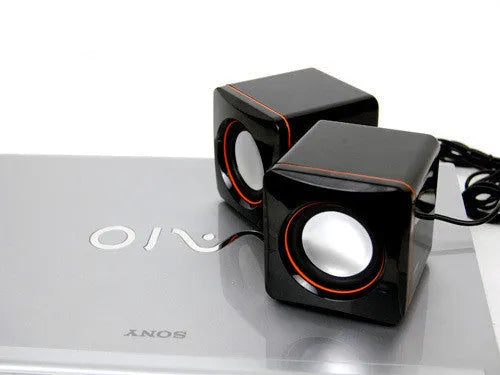 Small black square USB-powered 2.0 computer speaker on a desk.