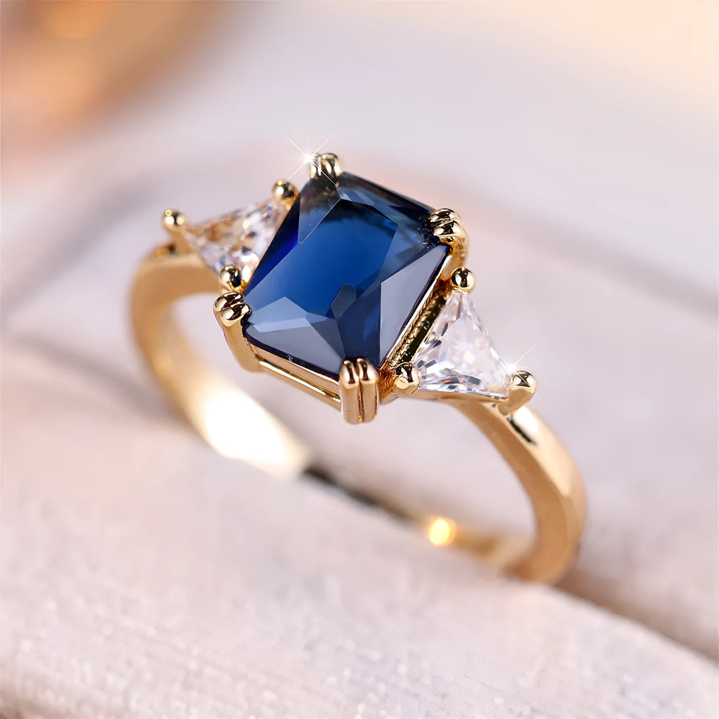 A gold sapphire blue rectangular copper ring for women on a jewellery display.