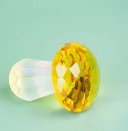 Small solid crystal mushroom ornament in modern geometric style on a wooden surface.