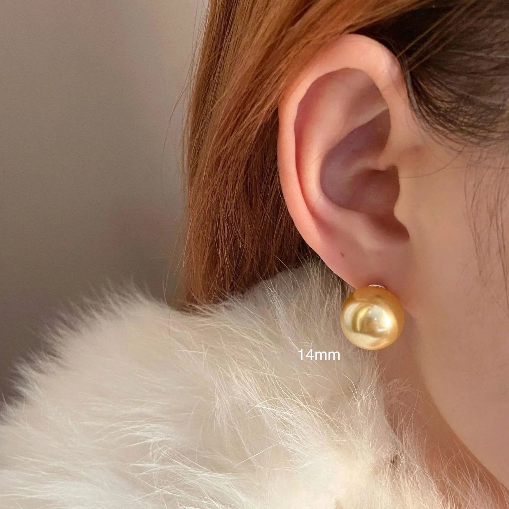 A pair of large pearl stud earrings with a geometric silver setting on a white background.
