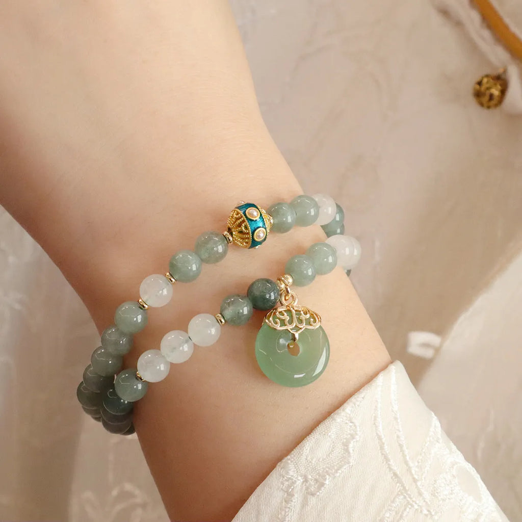 Close-up of a women's Myanmar jade bracelet with a geometric safety buckle pendant and lucky beads.