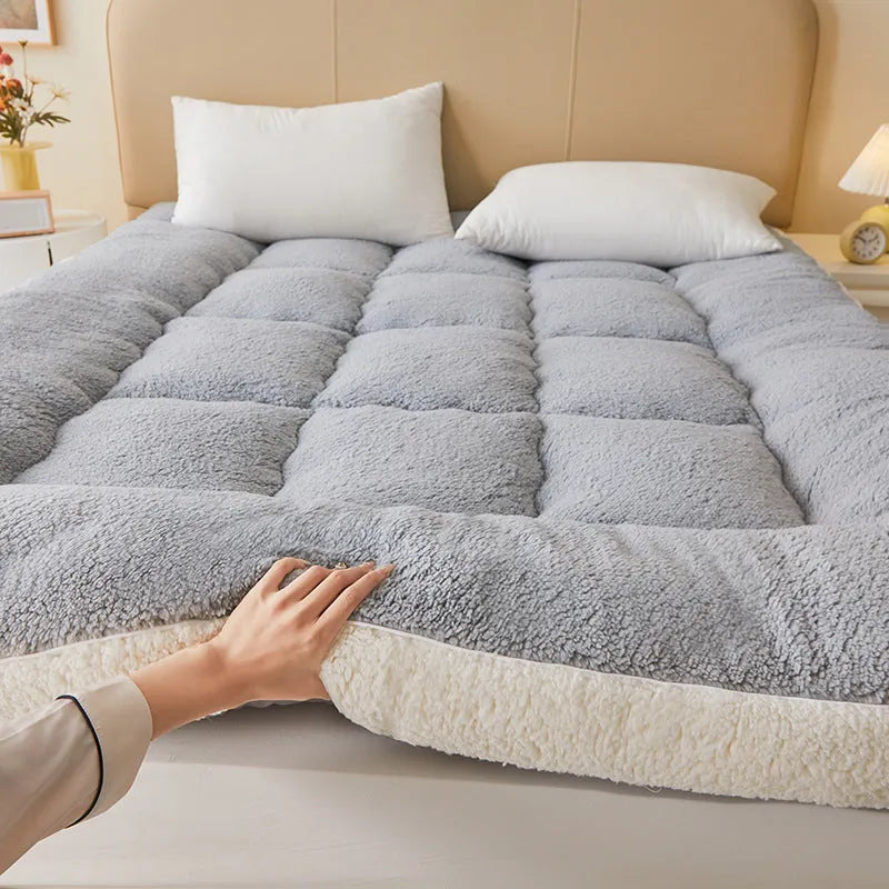 Lambswool mattress cushion with velvet cover in grey and white edge, on a bed