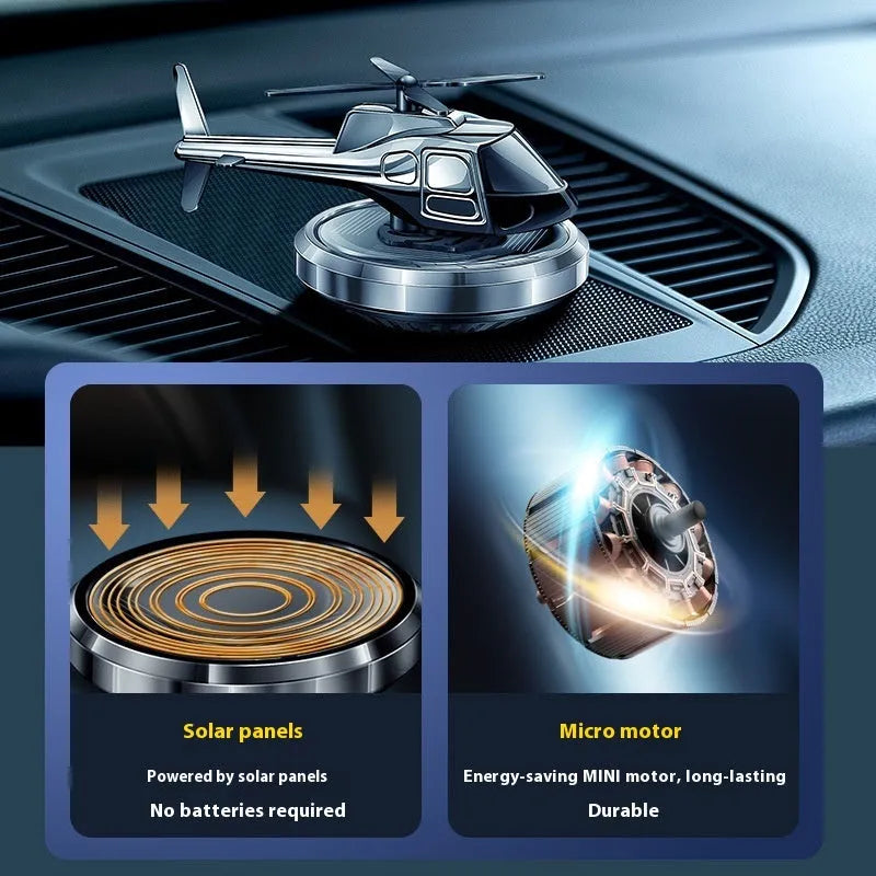 Silver metal solar-powered helicopter car air freshener rotating on a car dashboard.