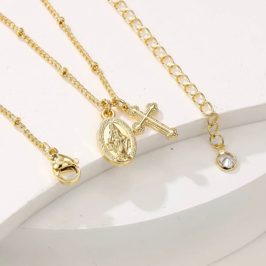 Geometric Virgin Mary cross pendant on a 45cm gold-coloured chain with an adjustable lobster clasp.