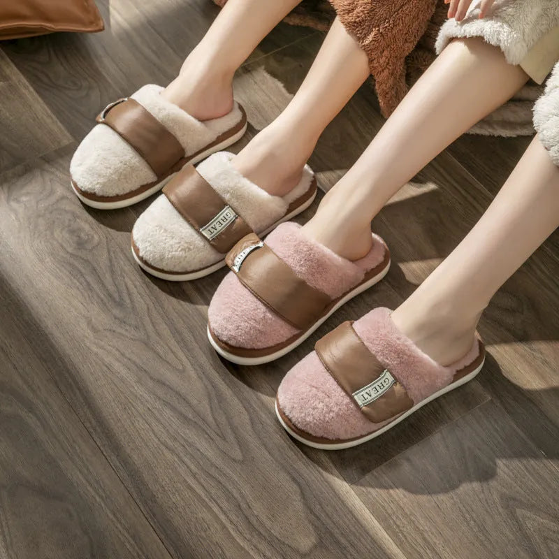 Beige plush velcro slippers with a round toe and non-slip plastic sole on a wooden floor.