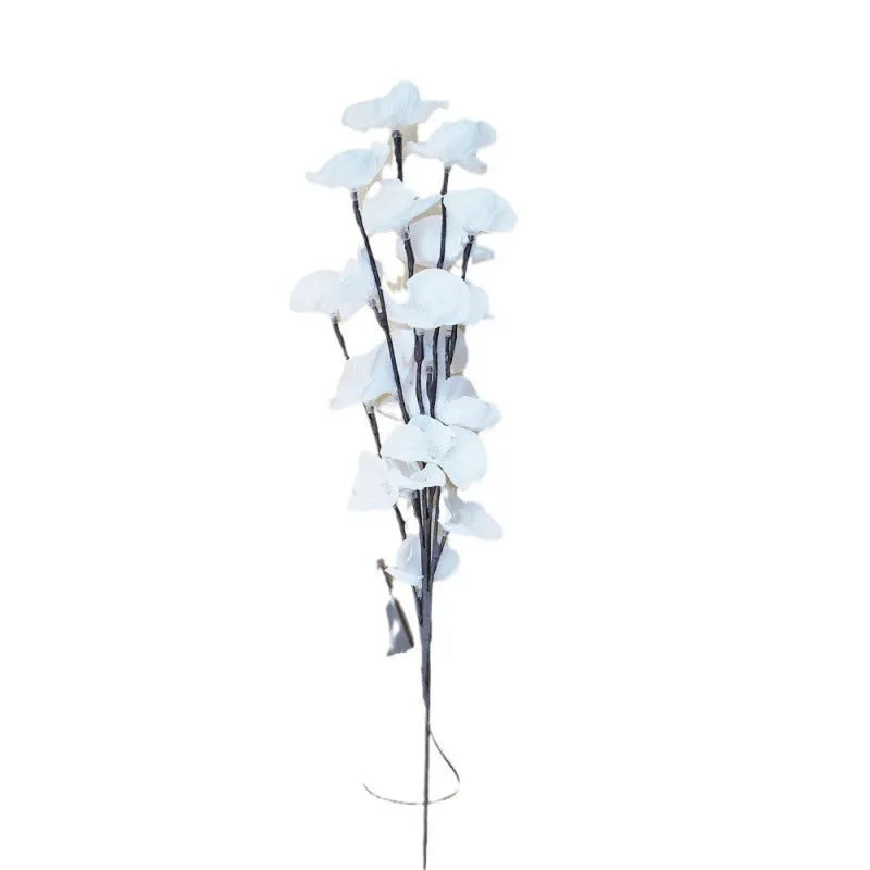 Pink LED phalaenopsis orchid branch light, 65cm tall, on a wooden surface emitting a warm glow.