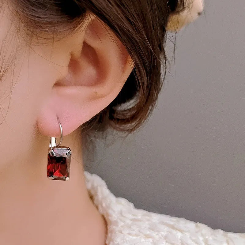 Square-shaped copper earrings with crystal decoration in red, yellow, or purple colours.