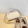 Genuine leather cylindrical crossbody phone bag in black, shown with single shoulder strap and visible sewing thread detail.