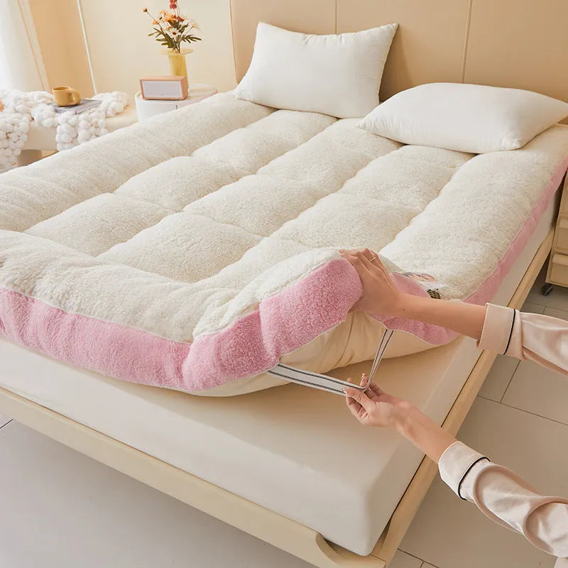 Lambswool mattress cushion with velvet cover in grey and white edge, on a bed