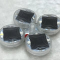 Colourful solar-powered LED valve light flashing on a car wheel hub.