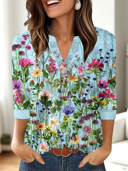 Woman wearing a loose-fit grey V-neck t-shirt with a colourful 3D geometric print, short sleeves.