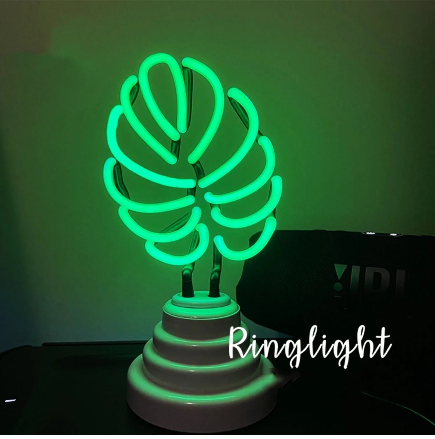 Minimalist white bamboo-shaped desk lamp emitting a soft green glow from its tube.