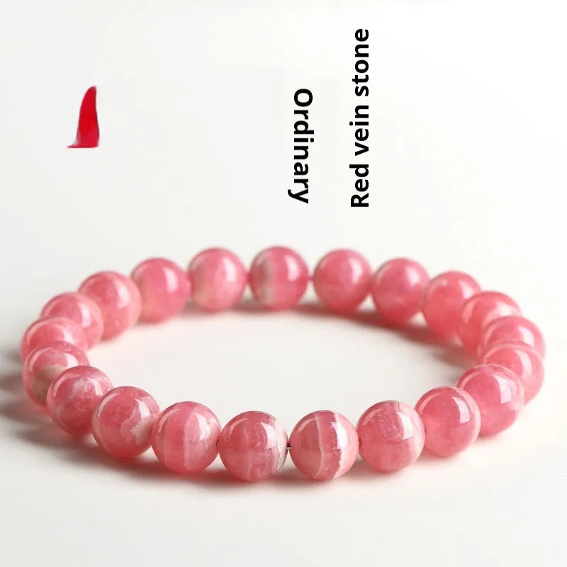 Women's geometric rhodochrosite crystal bracelet with a longevity lock clasp on a wrist.