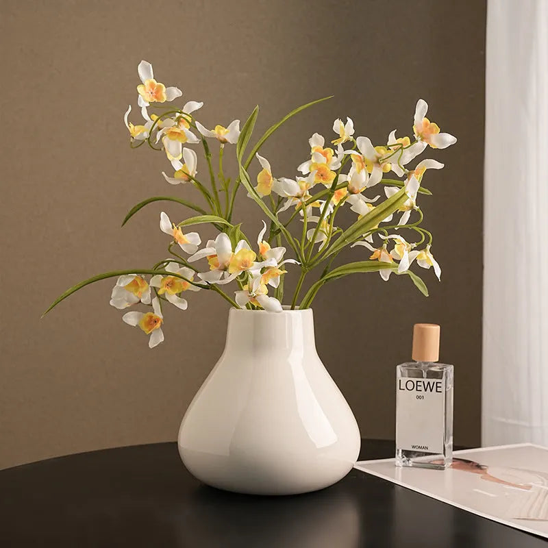 Modern round belly ceramic vase with coloured glaze, shown in black and white, some with artificial flowers.