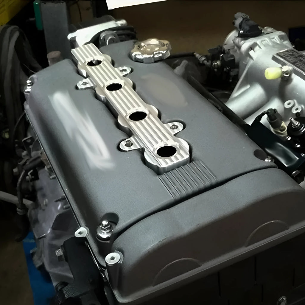 Aluminium engine harness housing bracket in blue, red, and silver, showing variants with and without mounting holes.