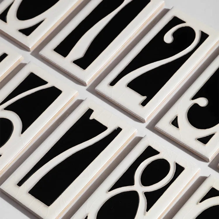 Handmade retro-style ceramic doorplate with large white enamel number 5 on a black background, showing scale.