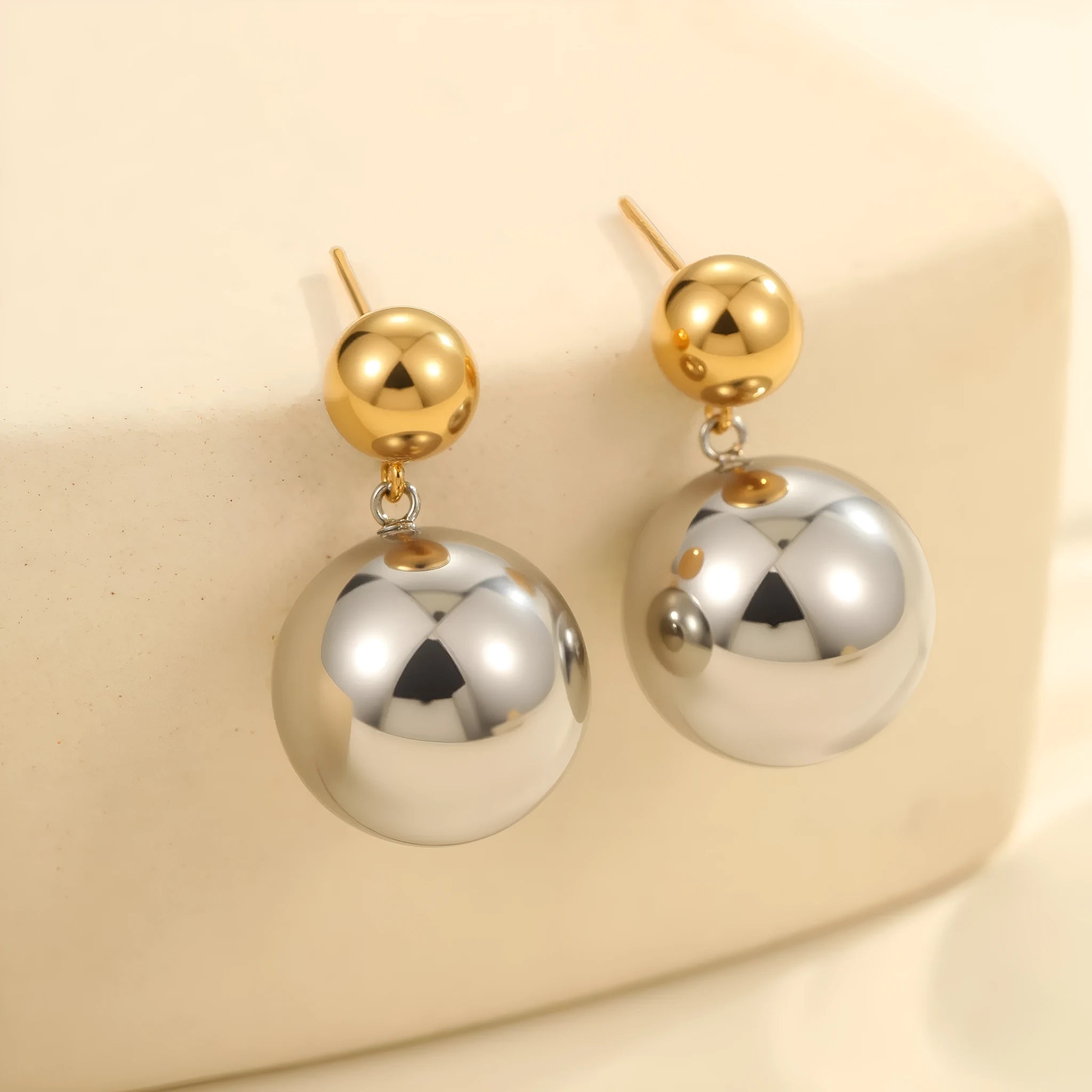 A pair of round bead geometric ear studs with a colour-block electroplated finish on stainless steel.