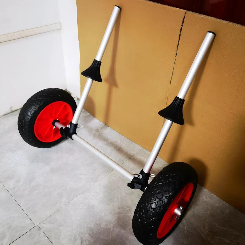 Foldable aluminium kayak cart with upright pole and rubber tyres on a beach, loaded with a yellow kayak.