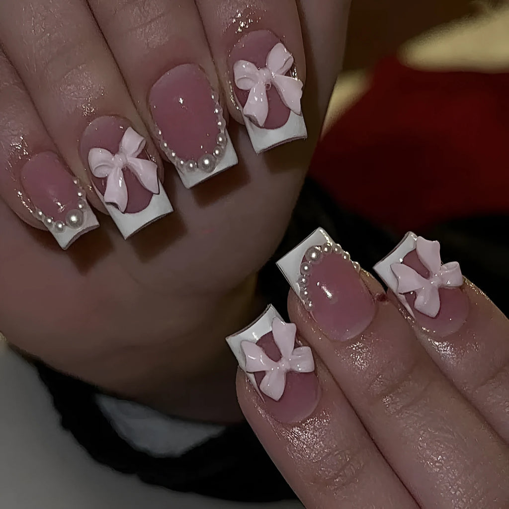 Set of short square press-on nails with white French tips, bow patterns, and tulip designs next to S274 glue bottles.