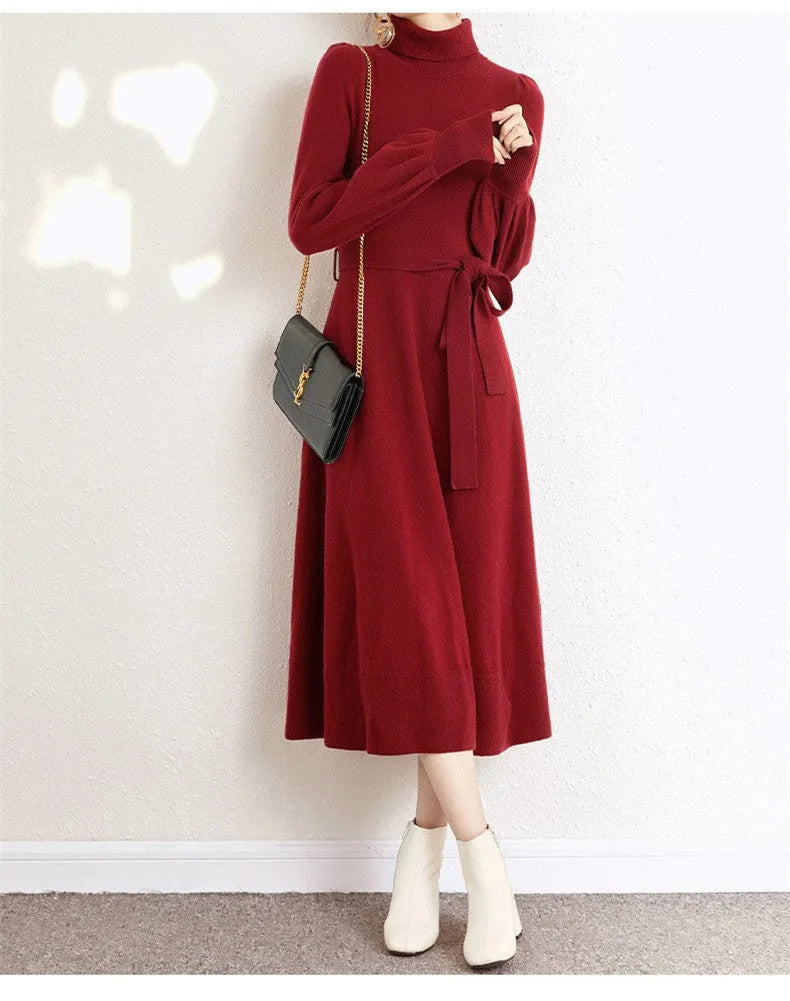 A woman wearing a rose red loose knitted turtleneck dress with a big hem midi skirt.