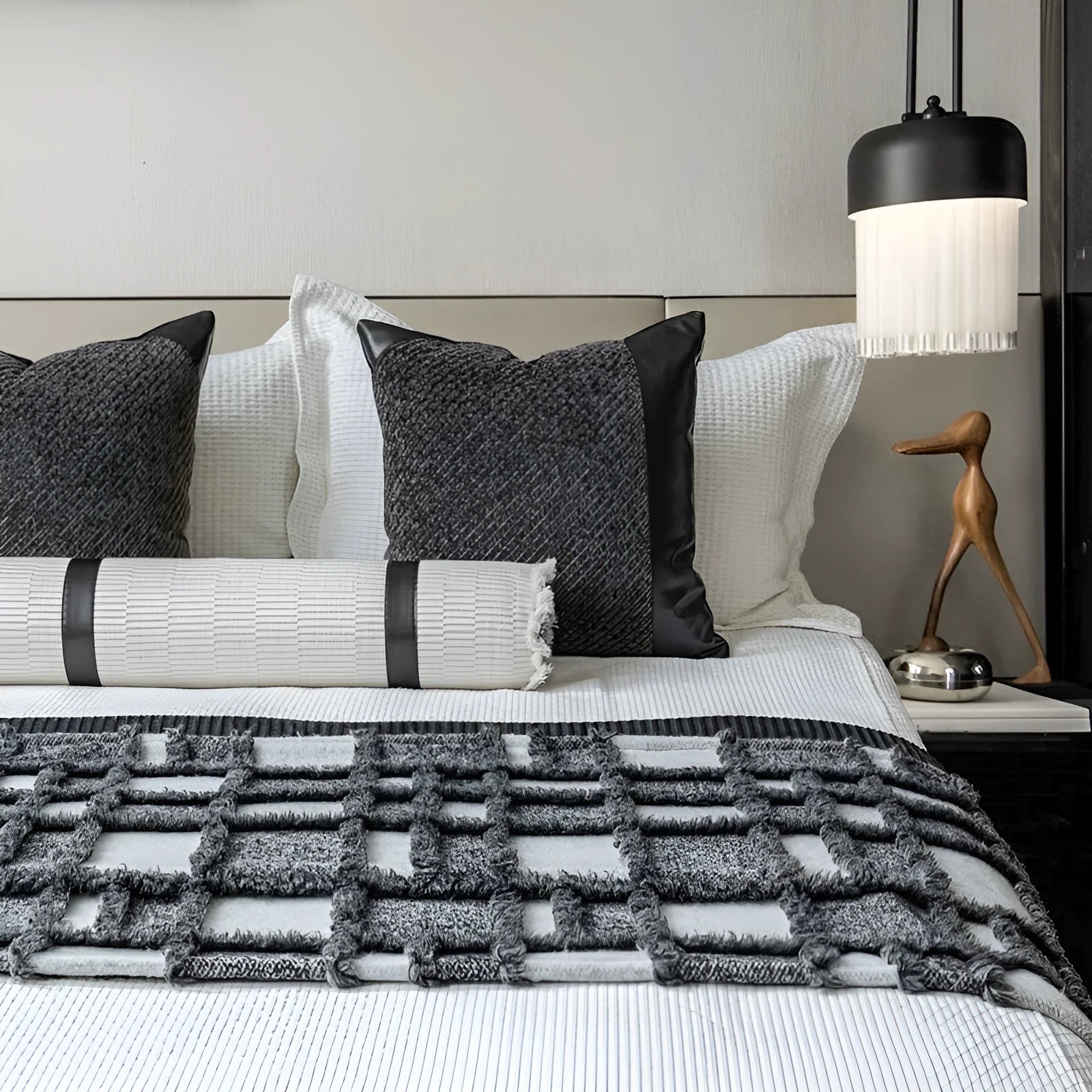 Modern gray and white plaid bed runner blanket with matching pillowcase and round leather-look pillow on a bed.