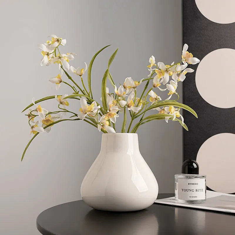 Modern round belly ceramic vase with coloured glaze, shown in black and white, some with artificial flowers.