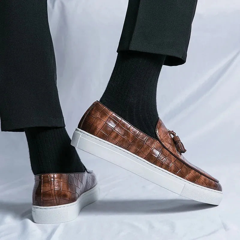 Men's black leather sneakers with a tassel detail on a round toe, shown on a white background.