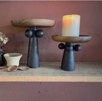 Nordic style round wooden tray with high legs for displaying candles and aromatherapy items.