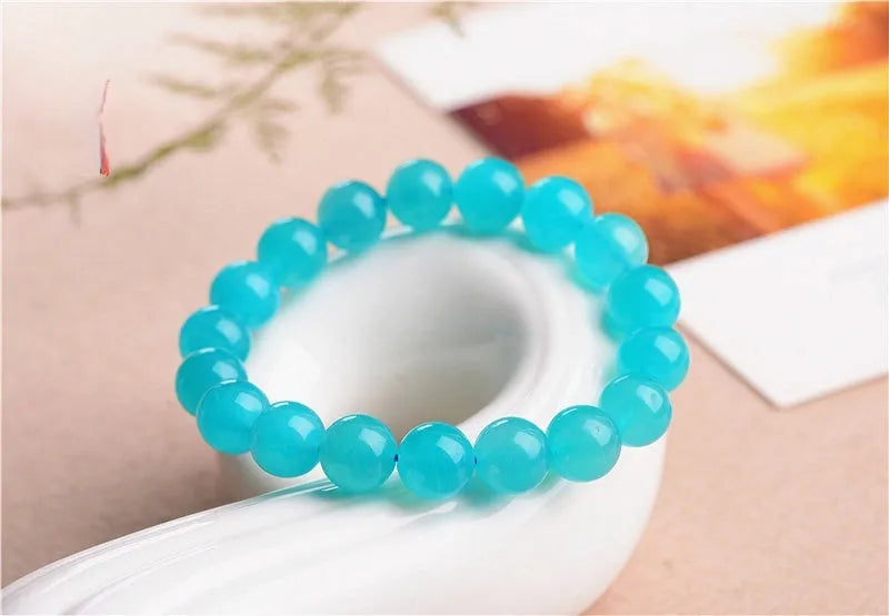 Loose natural Amazonite beads in ice blue colour, showing polished surfaces and irregular scattered shapes next to a finished bracelet.
