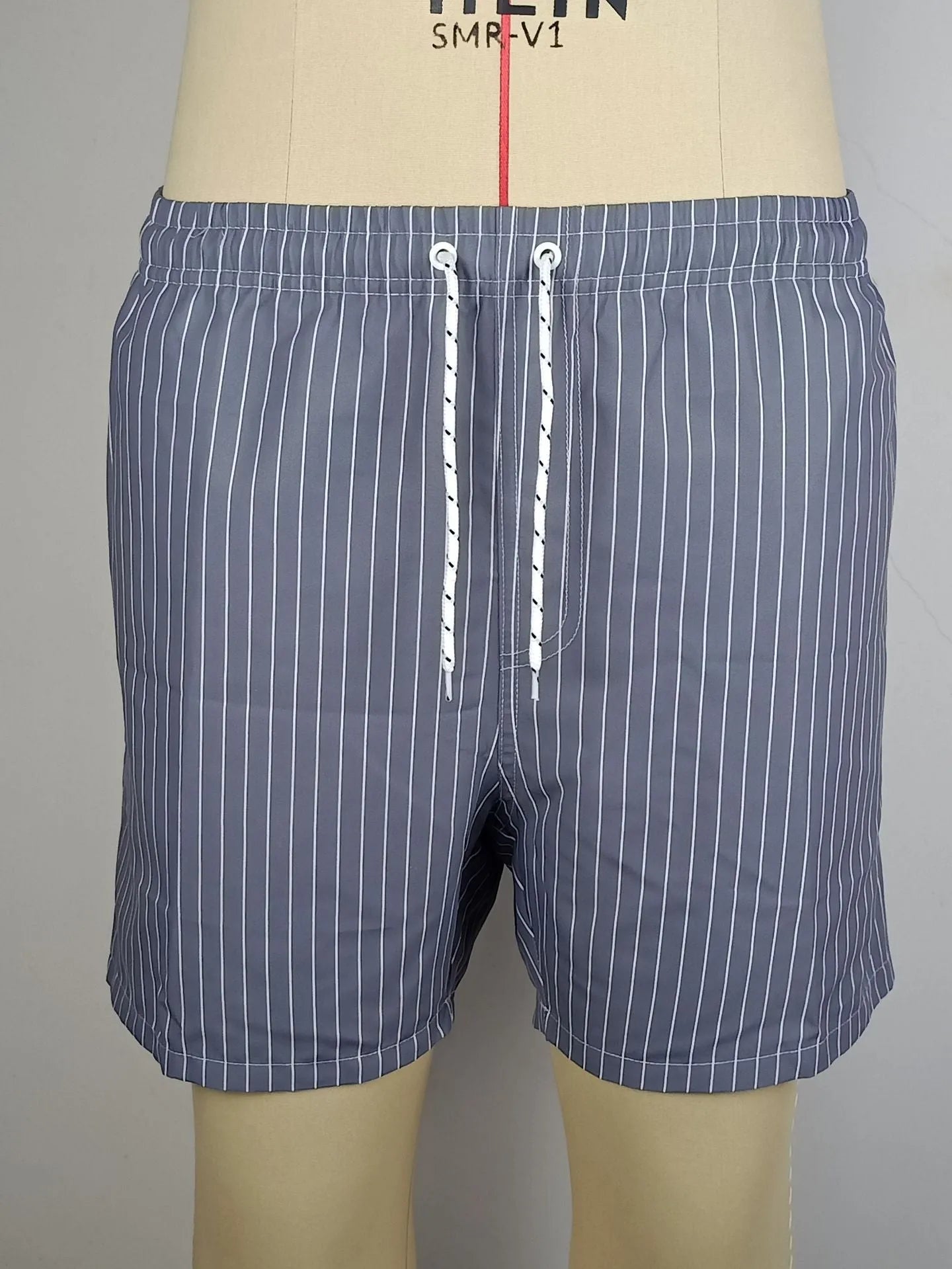 Man wearing grey striped polyester beach shorts with a straight leg opening
