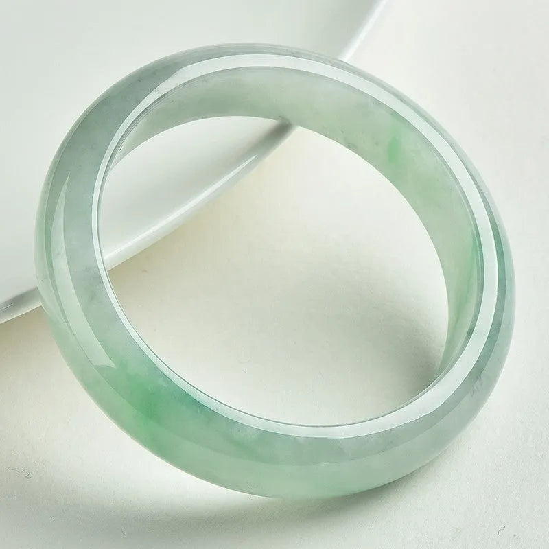 Light green jade bracelet on a wrist, showing its natural stone texture and colour.
