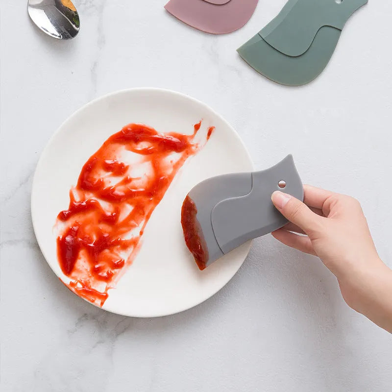Penguin-shaped soft blade kitchen scraper tool for cleaning plates and pans in green, grey, or pink colours