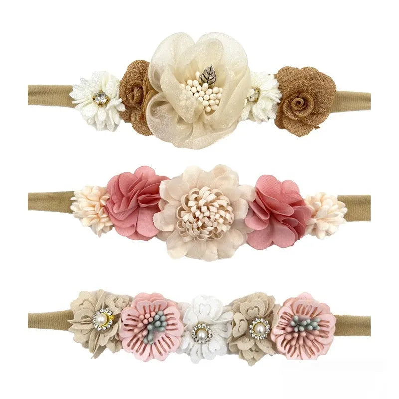 Three cloth flower-shaped hair bands for children in different styles on a light background