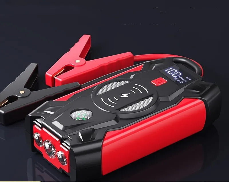 Red portable car battery jump starter with digital display, crocodile clips, and air pump hose.