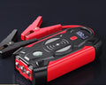 Red portable car battery jump starter with digital display, crocodile clips, and air pump hose.
