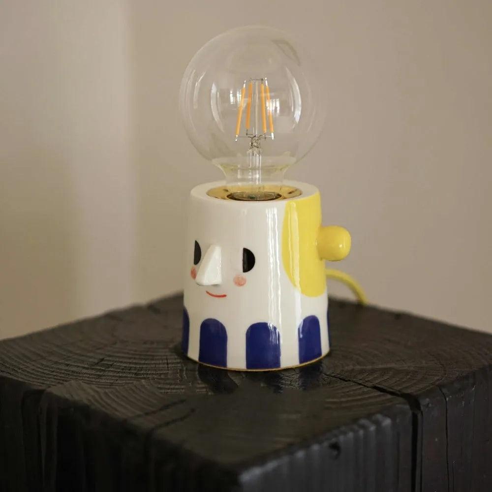 Handmade ceramic table lamp with white spherical shade on a wooden surface.