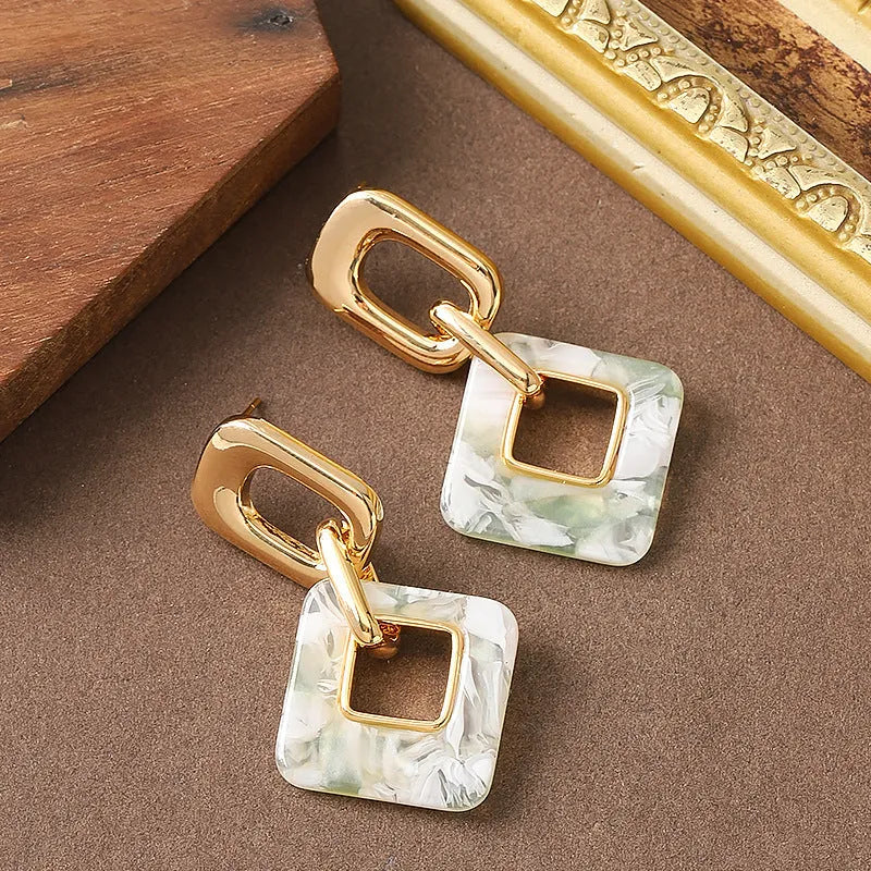 A pair of hollow geometric square copper earrings with chamfered corners on a white background.