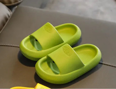 A pair of bright blue, one-piece EVA children's slippers with a textured non-slip sole, shown on a wooden floor.