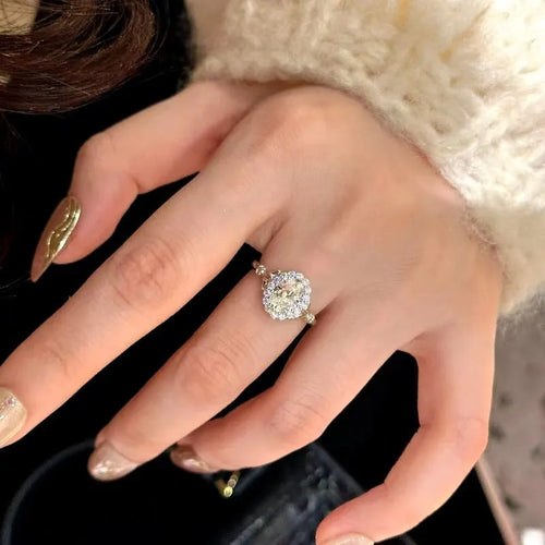 Geometric silver adjustable ring with an elliptical diamond on an index finger.