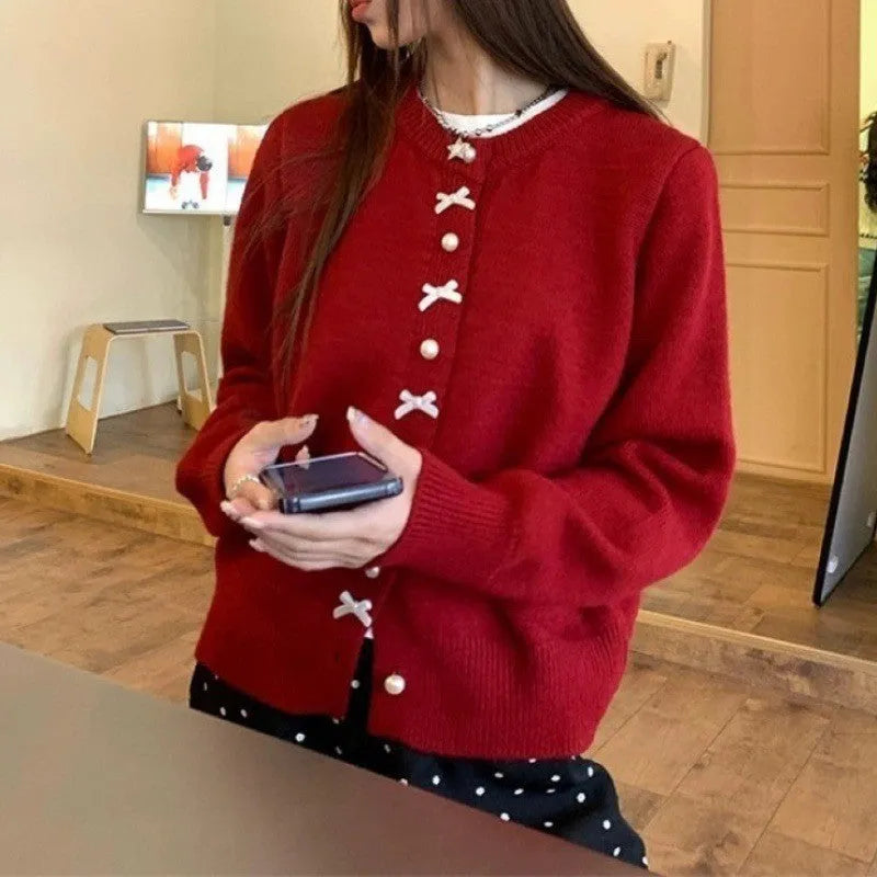 Women's cardigan sweater with a bow and pearl buttons in a solid colour.