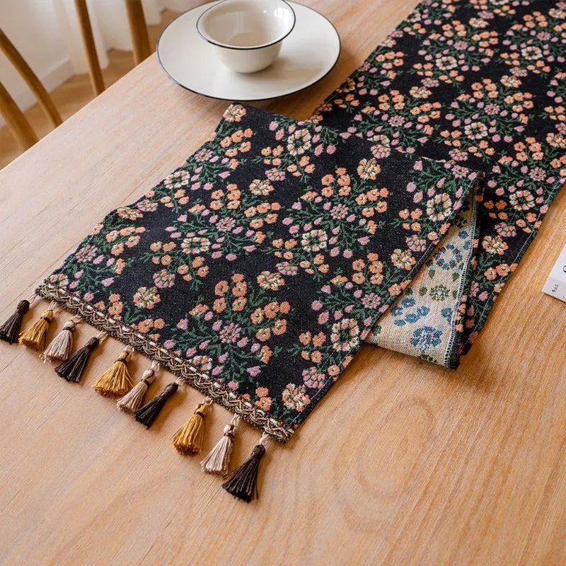 Nordic striped jacquard table runner with tassel on a dark wooden dining table.