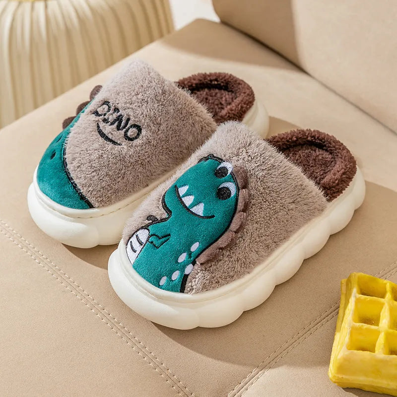 A pair of plush grey dinosaur slippers for indoor wear, showing soft cotton texture and graphic print.
