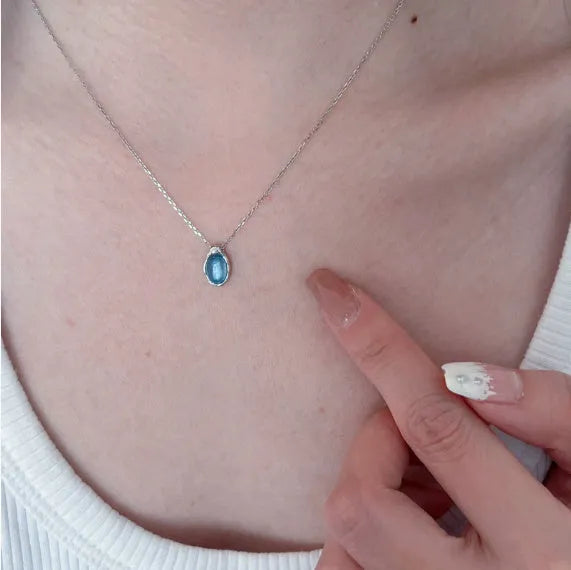 Navy blue water drop pendant necklace on a model, showing the adjustable cross chain and geometric copper design.