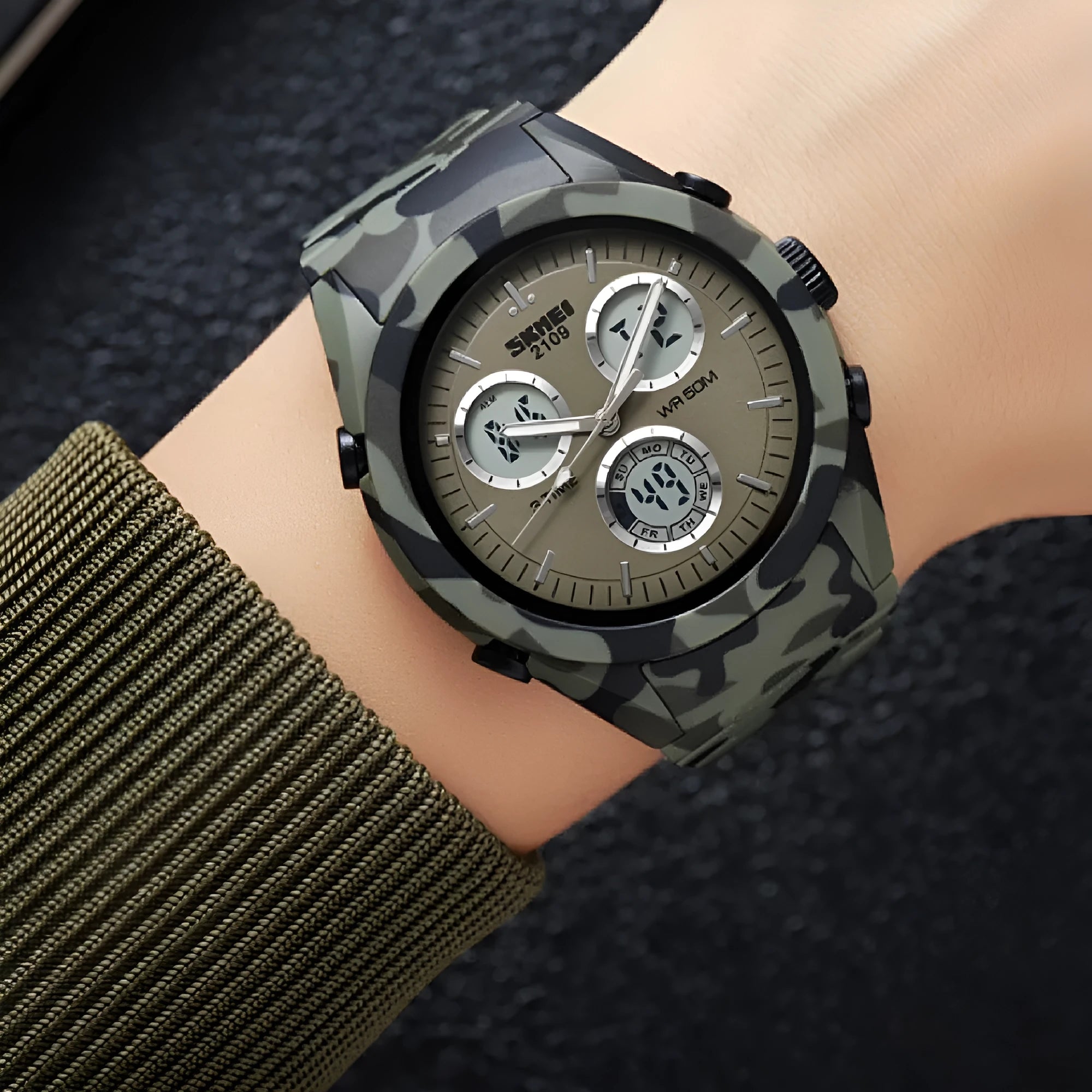 Casual digital watch with camouflage pattern strap and resin lens, showing stainless steel buttons on a wrist.
