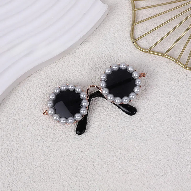 Round pearl-rimmed sunglasses for a cat or dog, shown in multiple colours including black, blue, and orange.