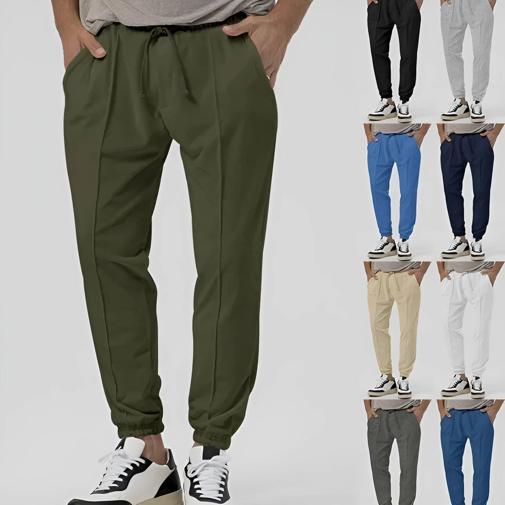 Man wearing grey tapered straight-leg casual sweatpants with a mid-rise elastic waistband.