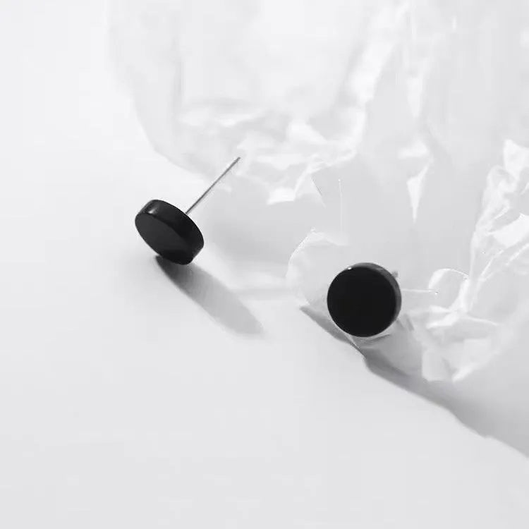 A pair of round, flat bone stud earrings in sterling silver, showing silver and black colour options.