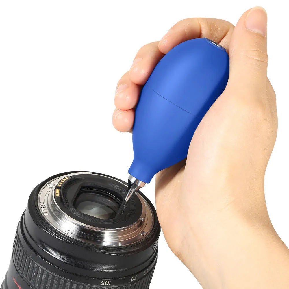Blue hand-held rubber dust blower cleaning tool with tapered nozzle, shown next to a mobile phone for scale